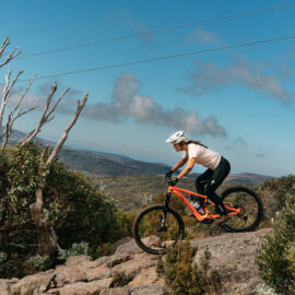 Cyclist riding over rock technical features at Falls Creek Mountain Bike Park